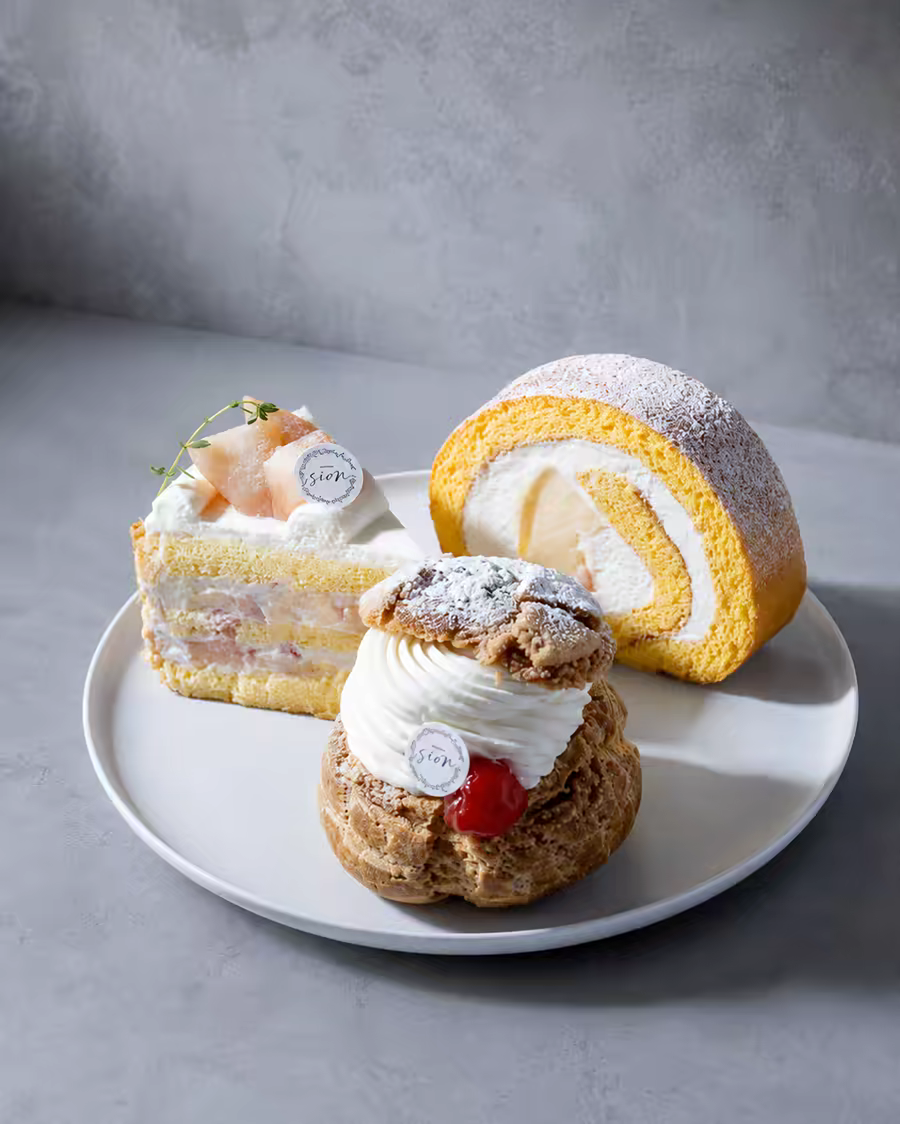 桃を使ったケーキやロールケーキなどを白い皿に並べたイメージ